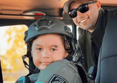 A child wears a Santa Maria Police SWAT helmet and vest while seated in the SWAT vehicle